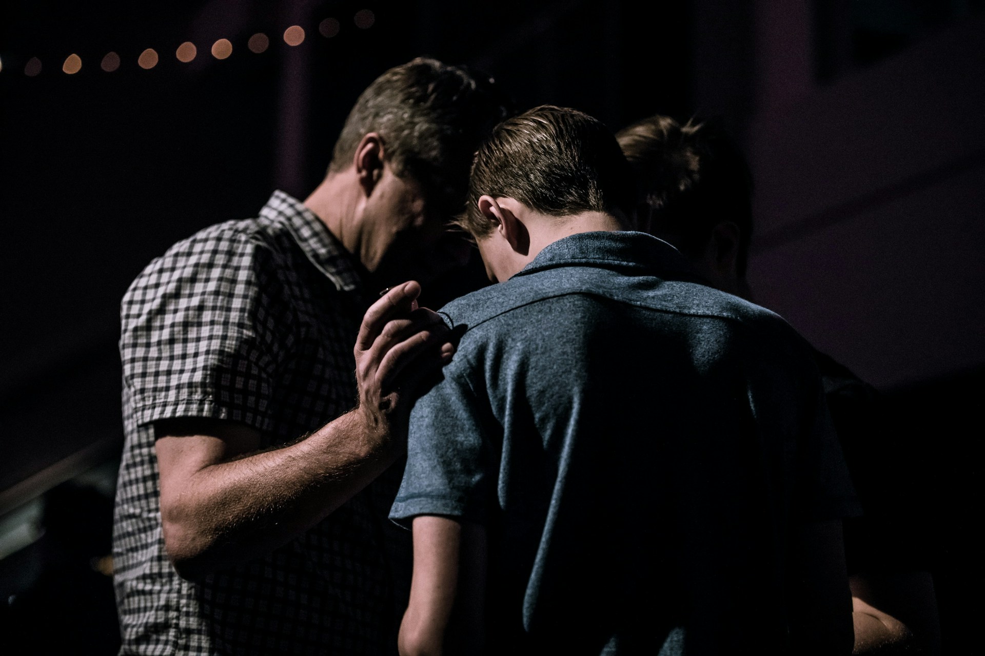 Someone praying with a hand on another person's shoulder